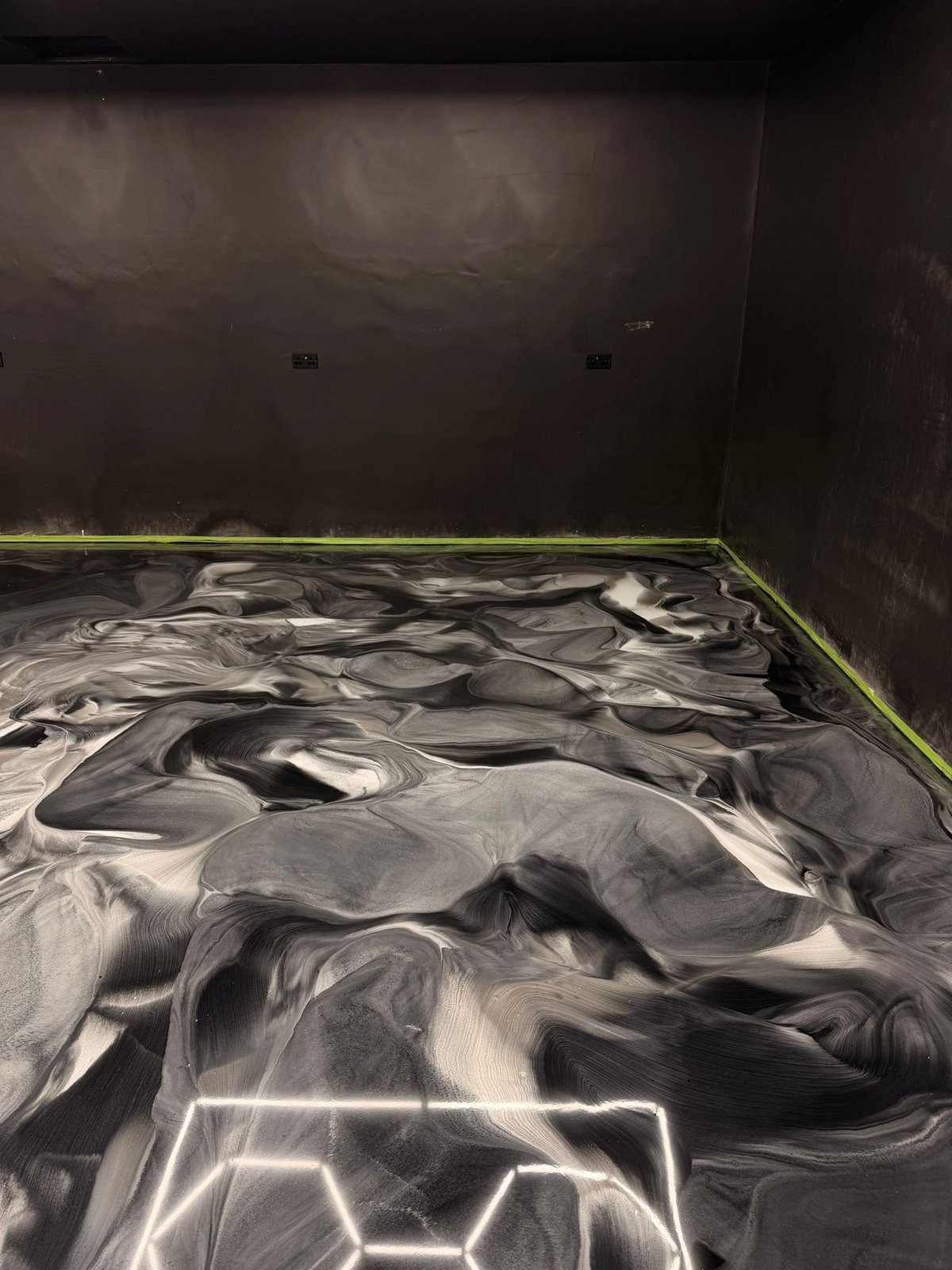 Dark room with black and white marbled floor featuring yellow trim along the edges and dark walls